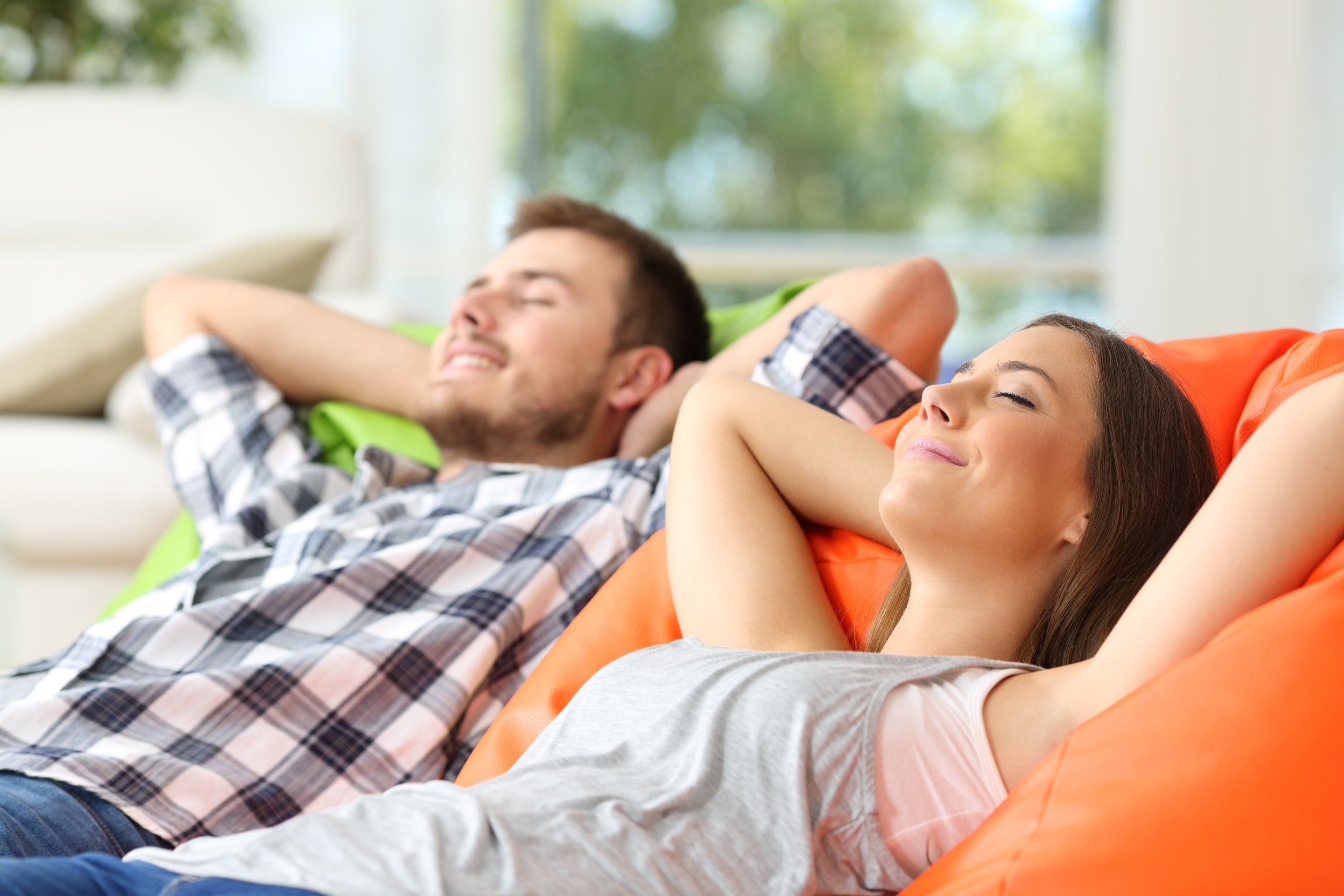 couple relaxing in zero gravity chairs at home