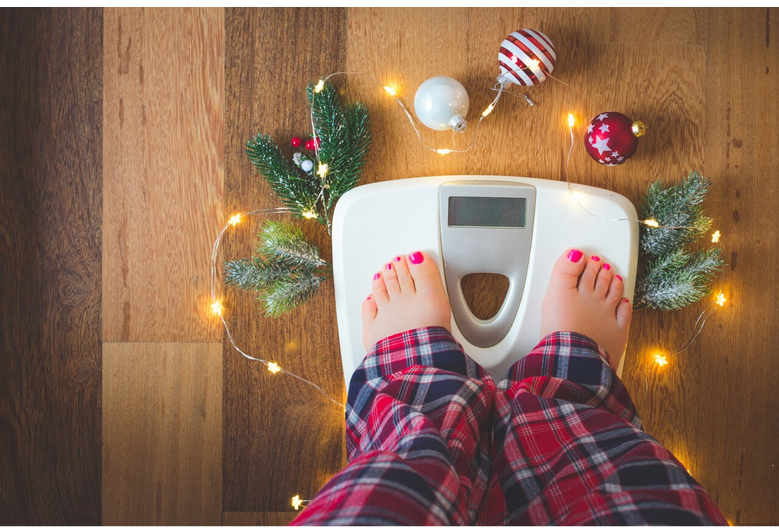 a woman weighing herself during the holidays