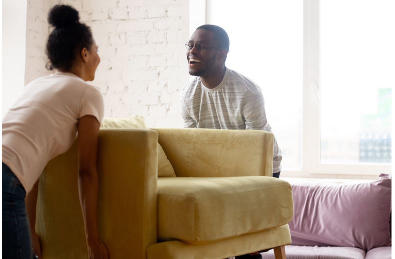 couple moving furniture into their first home