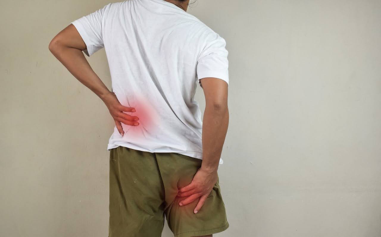 man holding his back with sciatica pain