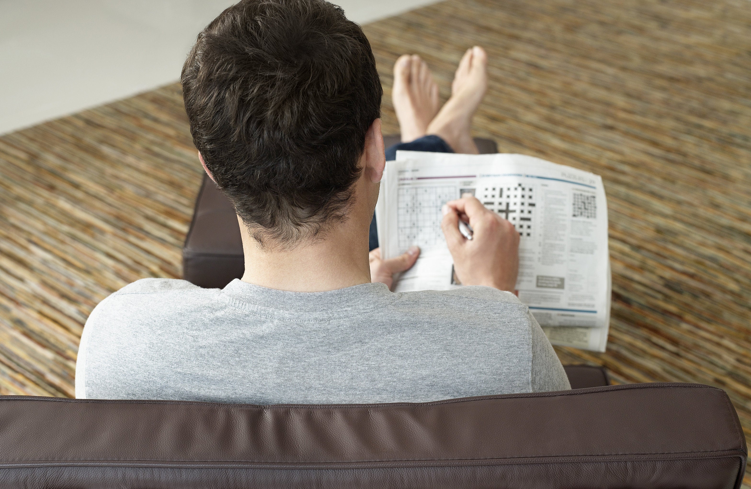 man working crossword puzzle in zero gravity chair