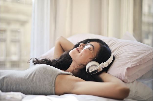 woman listening to her headphones in bed