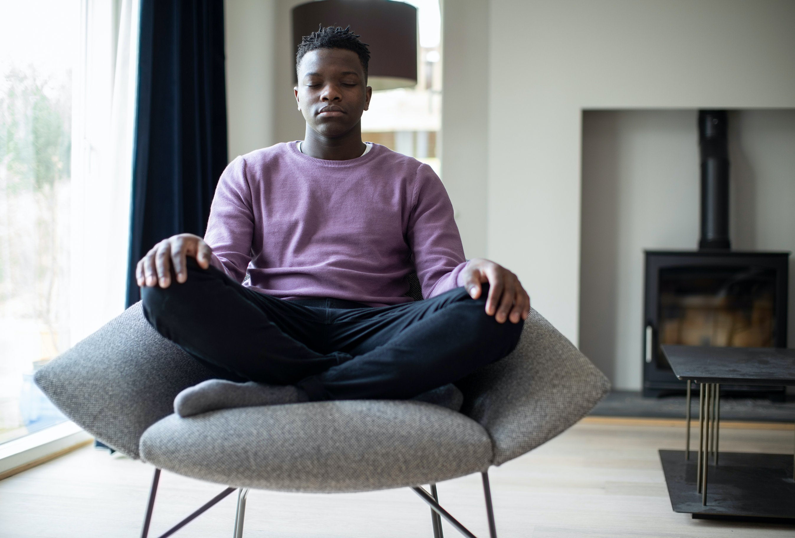 young man meditating in living room zen spot zero gravity chair